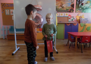 Lilianka częstuje Piotrka urodzinowym cukierkiem.